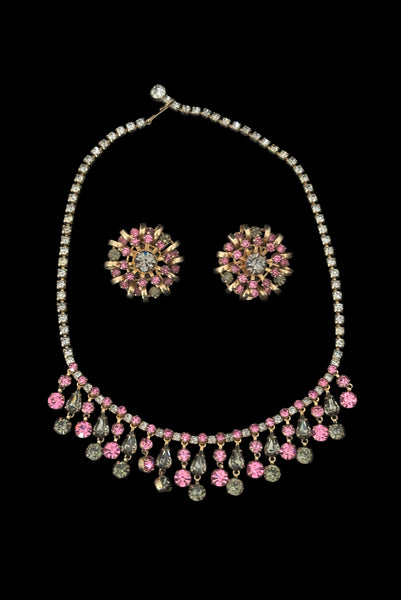 Vertical front view of 1950s vintage pink & gray round and pear cut rhinestone gold tone necklace and earrings demi-parure jewelry set.