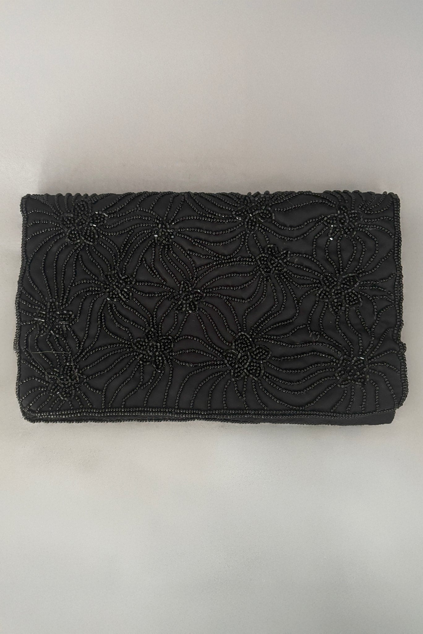 Vertical front view of 1960s vintage black satin floral beaded fold over clutch evening bag by Walborg.