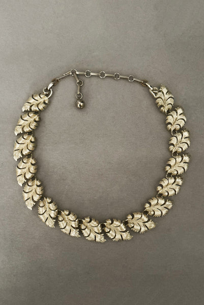 Vertical front view of 1950s vintage champagne gold tone leaf adjustable necklace by Lisner.