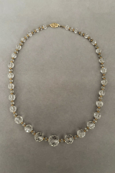 Vertical view of 1960s vintage graduated clear crystal bead necklace with gold tone spacers.