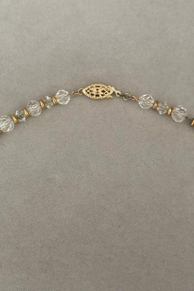 Detail view of 1960s vintage graduated clear crystal bead necklace with gold tone spacers. Showing a close-up of the filigree clasp.