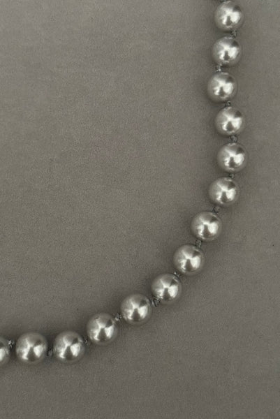 Detail view of 1980s vintage designer gray faux pearl bead necklace, by Monet. Showing a close-up of the beads with knots in between.