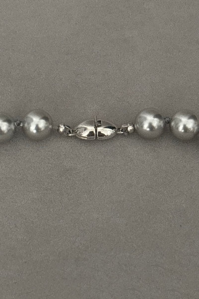 Detail view of 1980s vintage designer gray faux pearl bead necklace, by Monet. Showing a close-up of the silver tone clasp.
