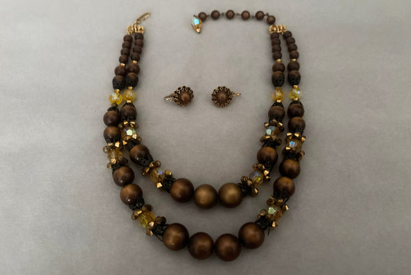 Horizontal view of 1950s vintage brown and yellow double strand beaded necklace and clip-on earrings demi parure set by Hobé.