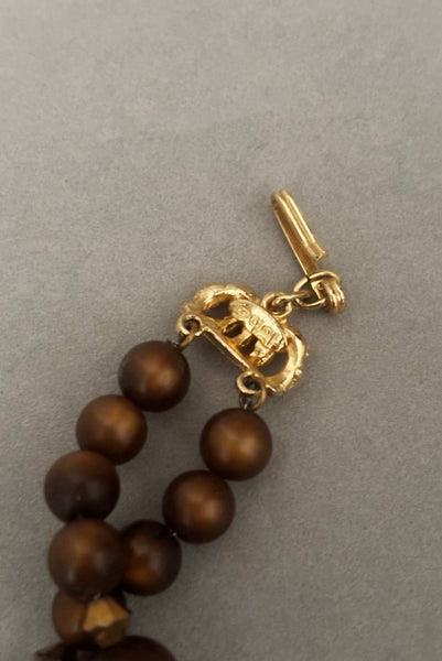 Detail view of 1950s vintage brown and yellow double strand beaded necklace and clip-on earrings demi parure set by Hobé. Showing a close-up of the hook closure and Hobé stamp,