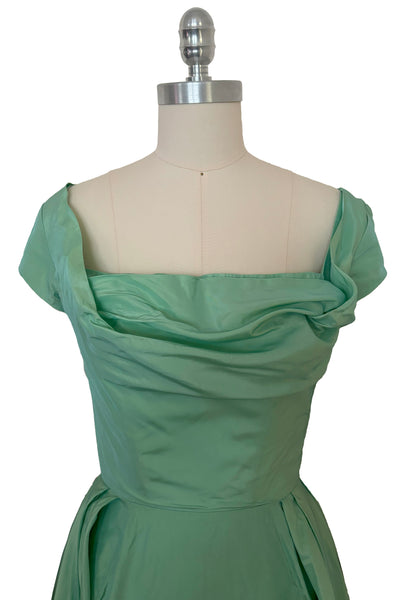 Bodice front view of 1950s vintage mint green iridescent taffeta shelf bust wiggle cocktail dress with balloon train by Kay Selig, extra extra small to extra small. Showing the cap sleeves, square neckline, and draped shelf bust.