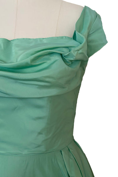 Detail view of 1950s vintage mint green iridescent taffeta shelf bust wiggle cocktail dress with balloon train by Kay Selig, extra extra small to extra small. Showing the cap sleeves, square neckline, and draped shelf bust.