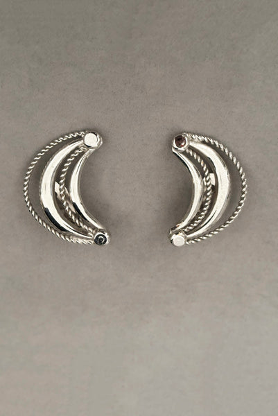 Vertical front view of 1980s vintage silver tone crescent clip-on statement earrings by Bergere.