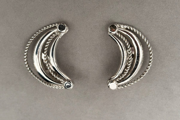 Horizontal front view of 1980s vintage silver tone crescent clip-on statement earrings by Bergere.