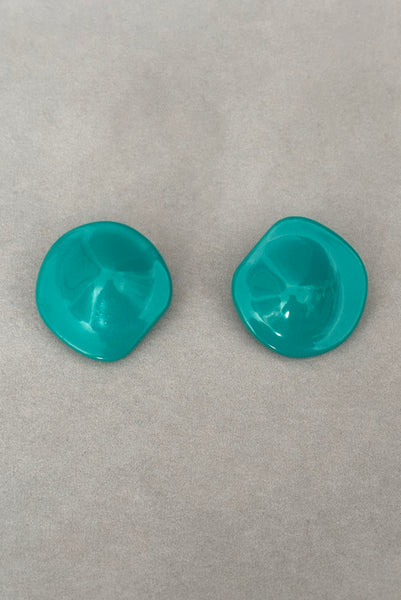 Vertical front view of 1980s vintage teal green irregular bumpy round plastic clip-on statement earrings.
