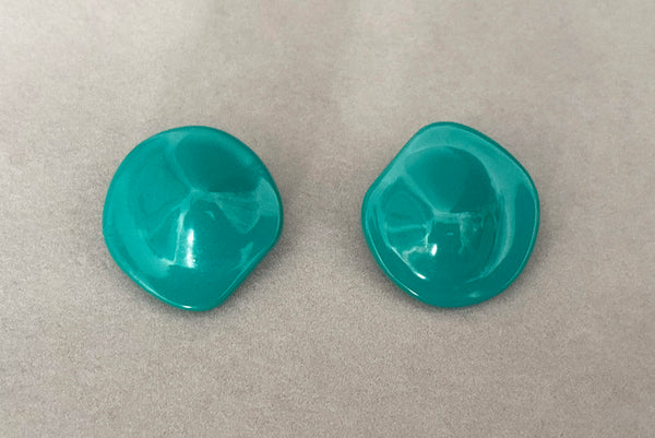 Horizontal front view of 1980s vintage teal green irregular bumpy round plastic clip-on statement earrings.