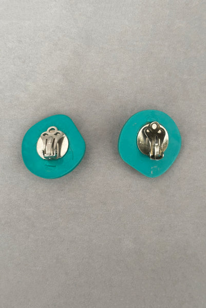 Vertical back view of 1980s vintage teal green irregular bumpy round plastic clip-on statement earrings.