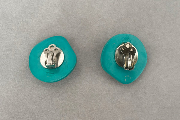 Horizontal back view of 1980s vintage teal green irregular bumpy round plastic clip-on statement earrings.