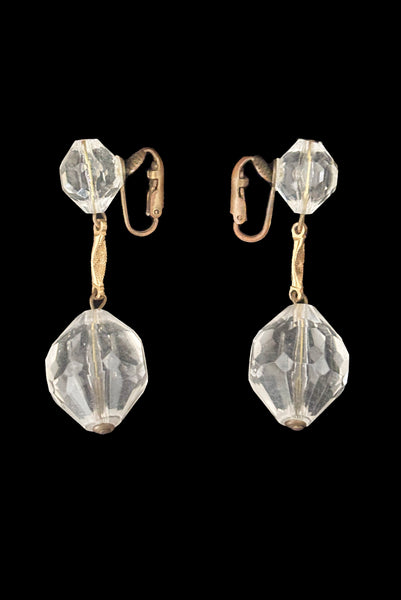 Vertical side view of 1960s vintage mod clear faceted Lucite bead and gold tone metal top and drop clip-on earrings.