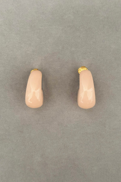 Vertical front view of 1980s vintage pink Lucite plastic and gold tone clip-on hoop earrings by Crown Trifari.