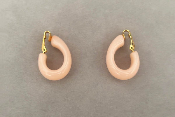 Horizontal side view of 1980s vintage pink Lucite plastic and gold tone clip-on hoop earrings by Crown Trifari.