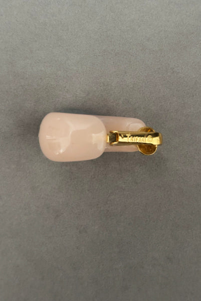 Detail view of 1980s vintage pink Lucite plastic and gold tone clip-on hoop earrings by Crown Trifari. Showing the Crown Trifari mark.