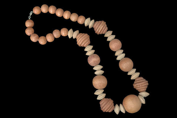 Horizontal view of 1980s vintage light and medium carved wood round, ridged bicone, and disk bead graduated two tone necklace.