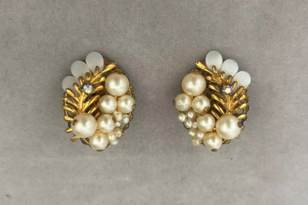 Horizontal front view of 1950s vintage cream faux pearl, white moonglow Lucite, iridescent rhinestone, and brass Oval filigree beaded clip-on earrings.