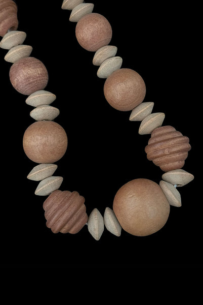 Detail view of 1980s vintage light and medium carved wood round, ridged bicone, and disk bead graduated two tone necklace. Showing a close-up of the largest beads.