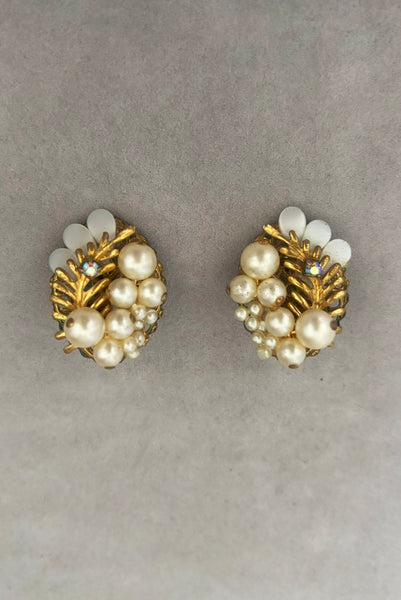 Vertical front view of 1950s vintage cream faux pearl, white moonglow Lucite, iridescent rhinestone, and brass Oval filigree beaded clip-on earrings.