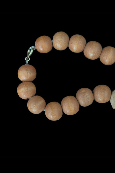 Detail view of 1980s vintage light and medium carved wood round, ridged bicone, and disk bead graduated two tone necklace. Showing a close-up of the silver tone spring ring clasp.