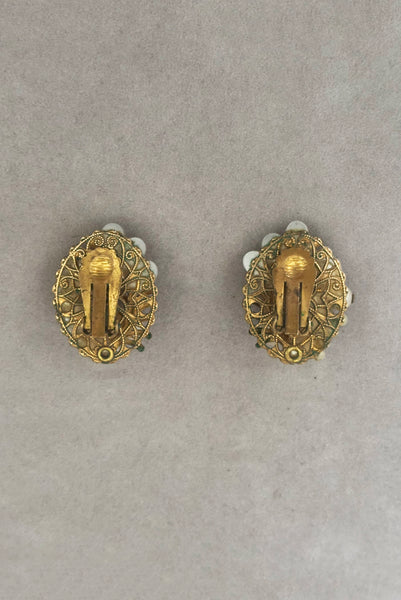 Vertical back view of 1950s vintage cream faux pearl, white moonglow Lucite, iridescent rhinestone, and brass Oval filigree beaded clip-on earrings.