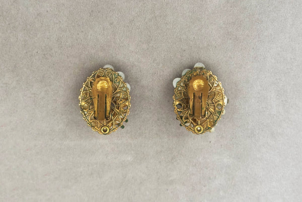 Horizontal back view of 1950s vintage cream faux pearl, white moonglow Lucite, iridescent rhinestone, and brass Oval filigree beaded clip-on earrings.