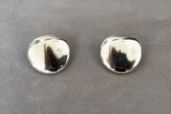 Horizontal front view of 1980s vintage polished silver tone irregular oval organic clip-on earrings.