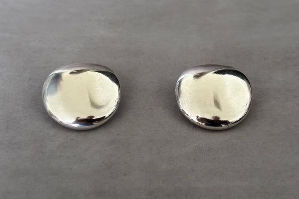 Horizontal perspective view of 1980s vintage polished silver tone irregular oval organic clip-on earrings.