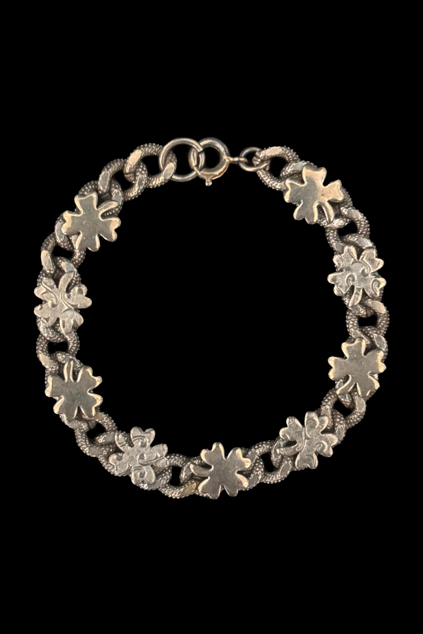 Vertical front view of 1960s vintage champagne gold tone four leaf clover lucky charm link bracelet.