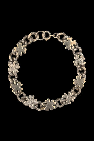 Vertical front view of 1960s vintage champagne gold tone four leaf clover lucky charm link bracelet.
