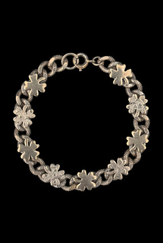 Vertical front view of 1960s vintage champagne gold tone four leaf clover lucky charm link bracelet.