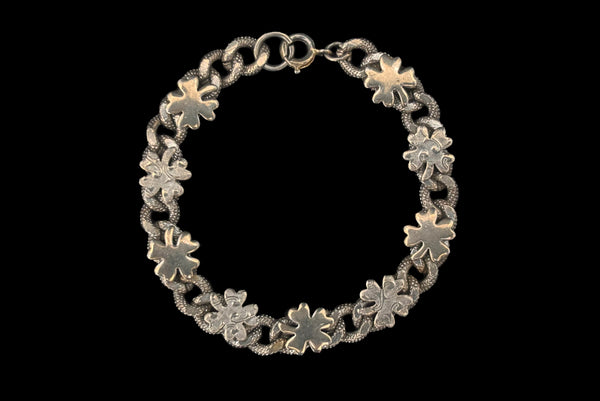 Horizontal front view of 1960s vintage champagne gold tone four leaf clover lucky charm link bracelet.