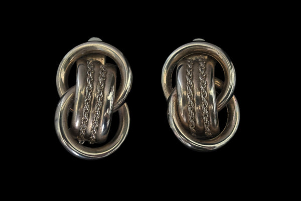 Horizontal front view of 1980s vintage gold tone interlocking hollow tube rope chain trimmed clip-on statement earrings.