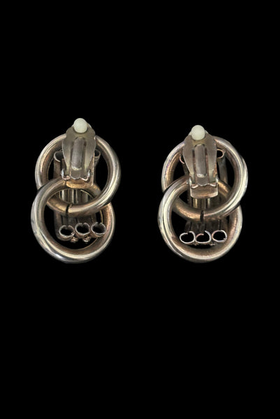 Vertical back view of 1980s vintage gold tone interlocking hollow tube rope chain trimmed clip-on statement earrings.