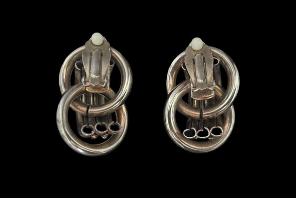 Horizontal back view of 1980s vintage gold tone interlocking hollow tube rope chain trimmed clip-on statement earrings.