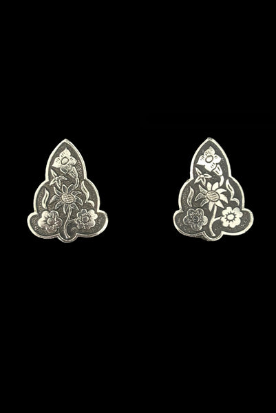 Vertical front view of 1960s vintage silver tone and black floral scalloped triangular clip-on earrings for unpierced ears.