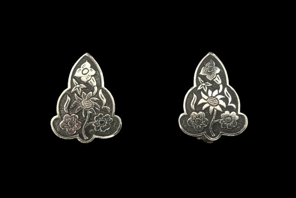 Horizontal front view of 1960s vintage silver tone and black floral scalloped triangular clip-on earrings for unpierced ears.