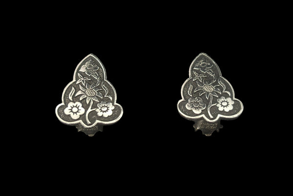 Vertical perspective view of 1960s vintage silver tone and black floral scalloped triangular clip-on earrings for unpierced ears.