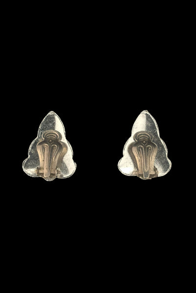 Vertical back view of 1960s vintage silver tone and black floral scalloped triangular clip-on earrings for unpierced ears.