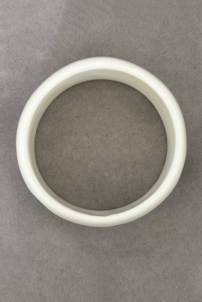 Vertical top view of 1980s vintage green and white polka dot plastic domed bangle bracelet.