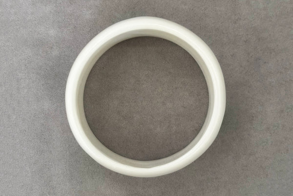 Horizontal top view of 1980s vintage green and white polka dot plastic domed bangle bracelet.