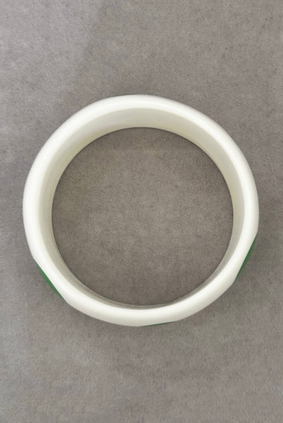 Vertical bottom view of 1980s vintage green and white polka dot plastic domed bangle bracelet.