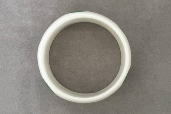 Horizontal bottom view of 1980s vintage green and white polka dot plastic domed bangle bracelet.