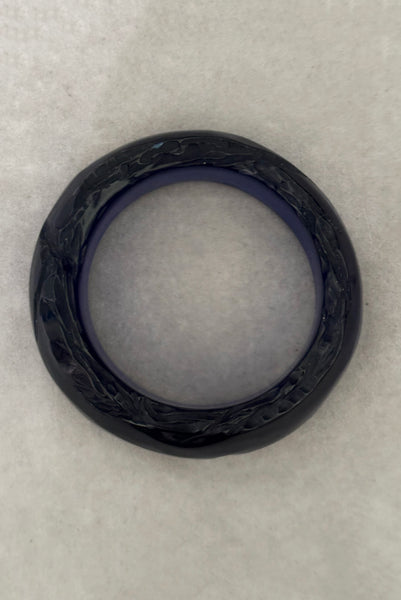 Vertical top view of 1980s vintage artisan carved translucent blue Lucite asymmetrical bangle bracelet.