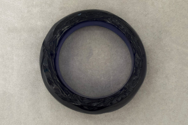 Horizontal top view of 1980s vintage artisan carved translucent blue Lucite asymmetrical bangle bracelet.