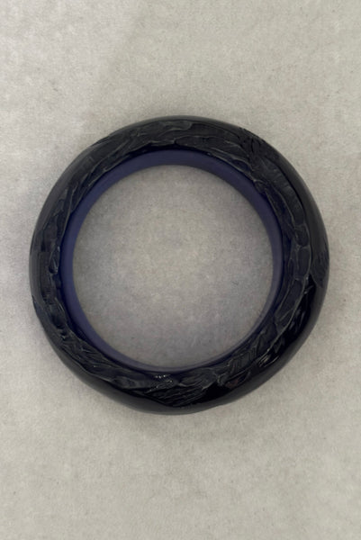 Vertical bottom view of 1980s vintage artisan carved translucent blue Lucite asymmetrical bangle bracelet.
