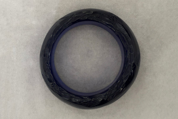 Horizontal bottom view of 1980s vintage artisan carved translucent blue Lucite asymmetrical bangle bracelet.