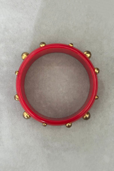 Vertical top view of 1940s vintage brass studded rich cherry red Bakelite statement bangle bracelet.